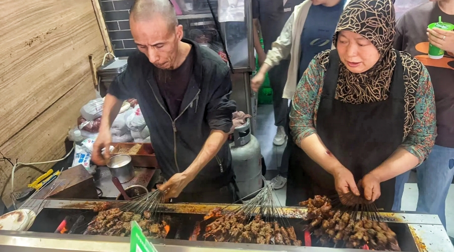 In Xi’an’s Muslim Quarter, a vendor prepares grilled halal skewers, a favorite local street food