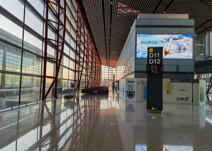 Spacious corridor with red steel frames and floor-to-ceiling glass at Beijing Capital International Airport
